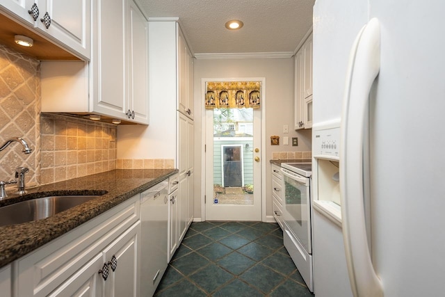 kitchen featuring sink, dark stone countertops, white appliances, white cabinets, and dark tile patterned flooring