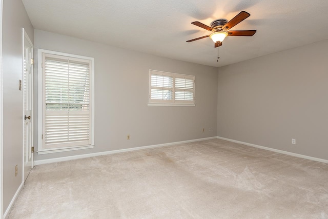 carpeted empty room with ceiling fan, plenty of natural light, and a textured ceiling