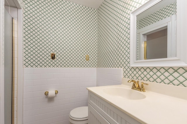 bathroom with vanity, tile walls, and toilet