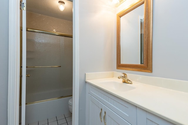 full bathroom with tile patterned floors, a textured ceiling, combined bath / shower with glass door, toilet, and vanity