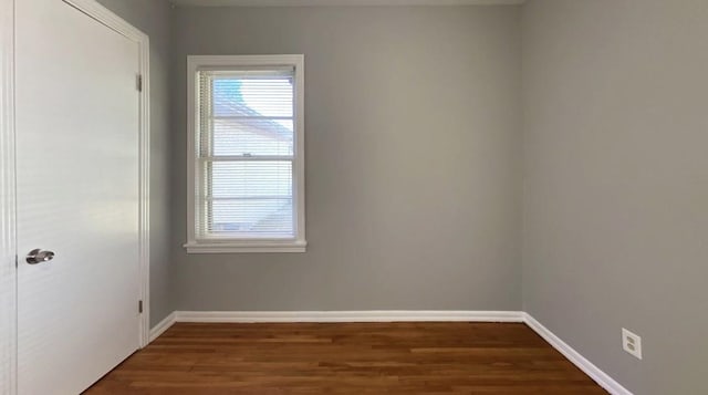 spare room featuring dark wood-style floors and baseboards