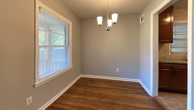 unfurnished dining area featuring dark wood-type flooring and a chandelier