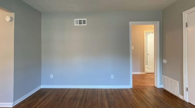 spare room with dark wood-style floors, baseboards, and visible vents