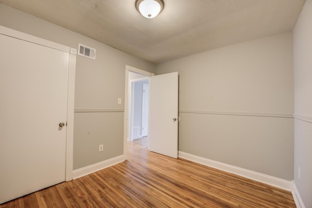 unfurnished bedroom with visible vents, baseboards, and wood finished floors