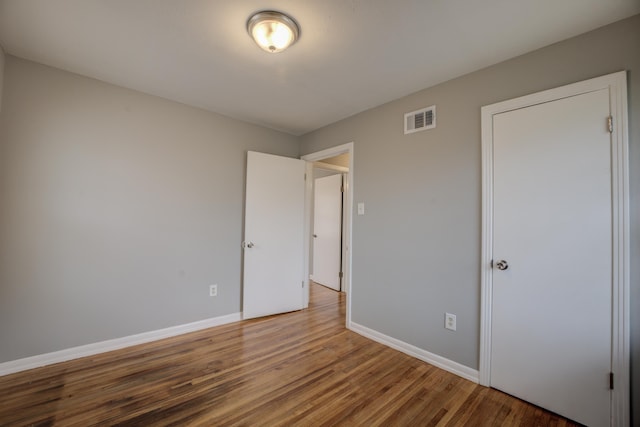 unfurnished bedroom featuring wood finished floors, visible vents, and baseboards