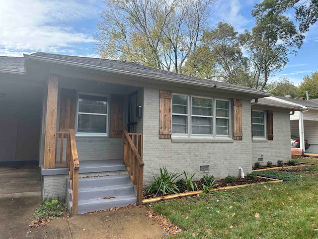 view of front of property featuring brick siding, a shingled roof, a front yard, crawl space, and driveway