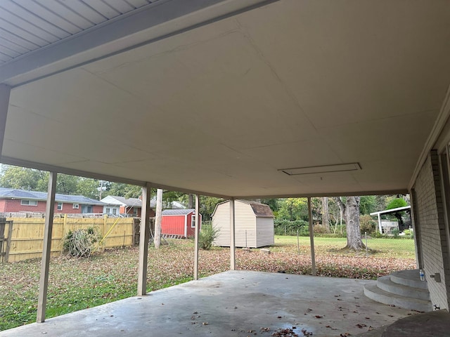 view of patio with a carport, an outbuilding, fence, and a shed