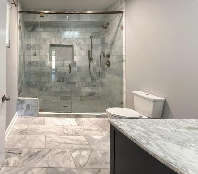 bathroom featuring a stall shower, marble finish floor, vanity, and toilet