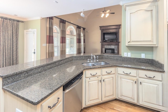 kitchen with light hardwood / wood-style floors, kitchen peninsula, sink, stainless steel dishwasher, and dark stone countertops