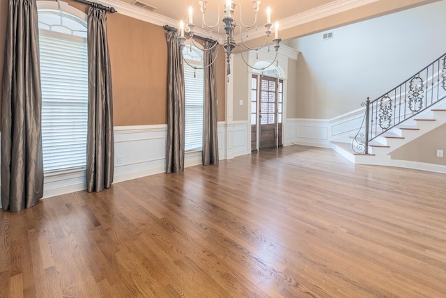 unfurnished room with hardwood / wood-style flooring, a notable chandelier, and ornamental molding