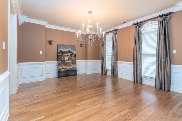 unfurnished dining area featuring light hardwood / wood-style floors, a chandelier, and crown molding