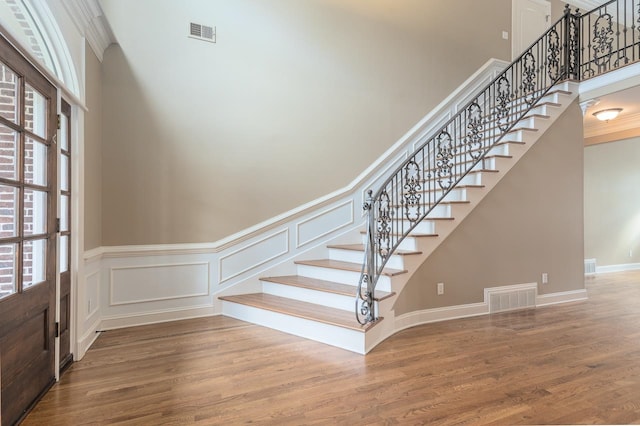 stairs with hardwood / wood-style flooring and a towering ceiling