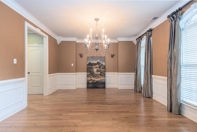 unfurnished dining area with ornamental molding, light hardwood / wood-style flooring, and a notable chandelier