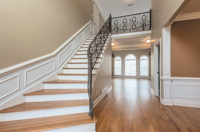 stairway with ornamental molding, wood-type flooring, and ornate columns