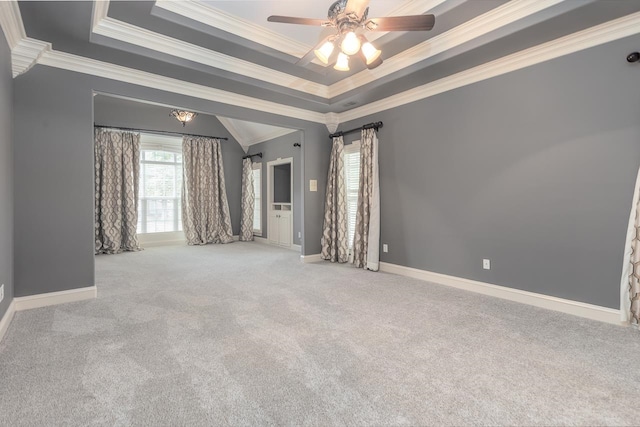 carpeted spare room with ceiling fan, crown molding, and a tray ceiling