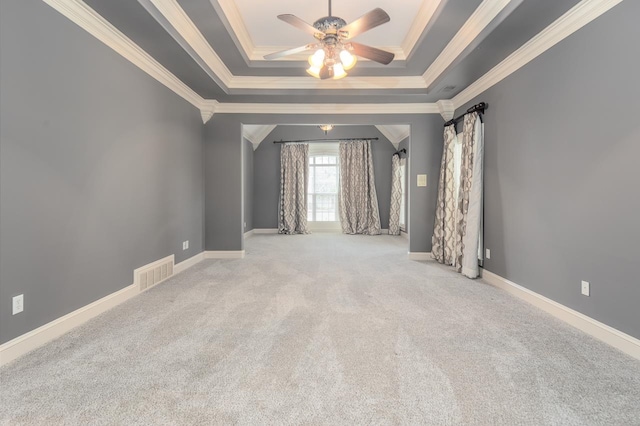 unfurnished room with ceiling fan, light colored carpet, crown molding, and a tray ceiling