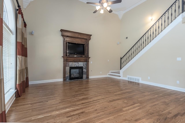 unfurnished living room featuring ornamental molding, hardwood / wood-style floors, a fireplace, and a high ceiling