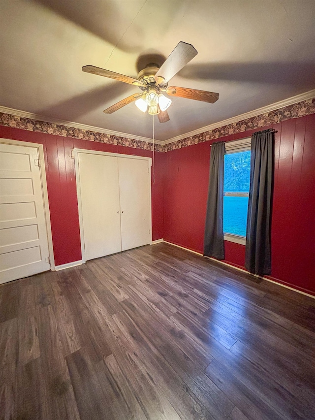 unfurnished bedroom featuring dark wood-type flooring, a closet, ornamental molding, and ceiling fan