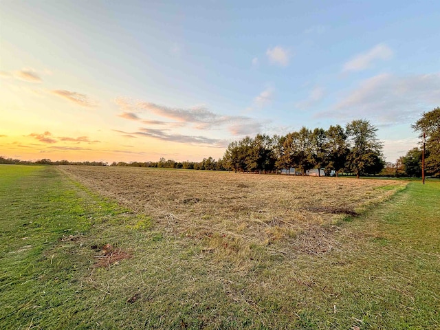 yard at dusk featuring a rural view