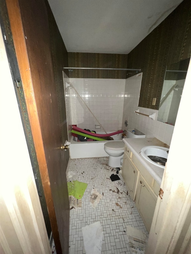 full bathroom featuring toilet, tile walls, tile patterned flooring, tiled shower / bath combo, and vanity