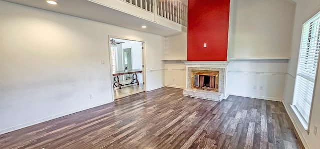 unfurnished living room featuring dark wood-type flooring and ceiling fan