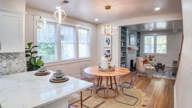 dining space with light wood-type flooring, a notable chandelier, and a fireplace