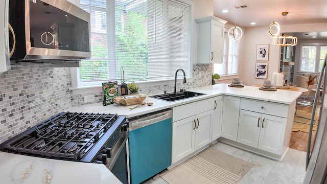 kitchen with sink, appliances with stainless steel finishes, backsplash, decorative light fixtures, and white cabinets