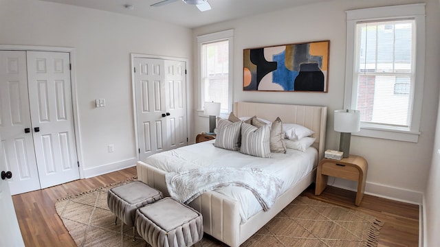 bedroom with multiple closets, hardwood / wood-style floors, and ceiling fan