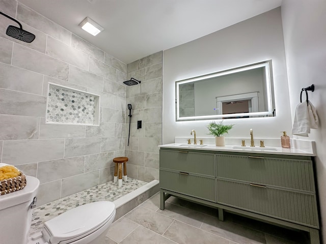 bathroom with tile patterned floors, vanity, toilet, and tiled shower