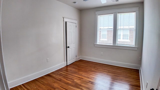 empty room with a wealth of natural light, dark wood-type flooring, and ceiling fan