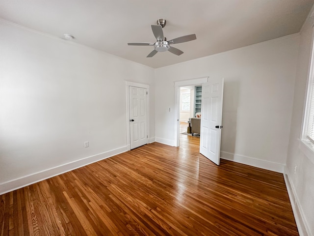 unfurnished bedroom featuring dark hardwood / wood-style flooring, ceiling fan, and crown molding