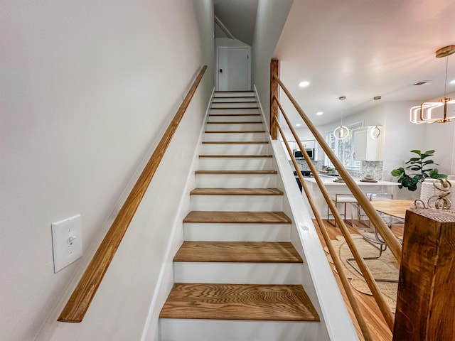 stairway featuring an inviting chandelier