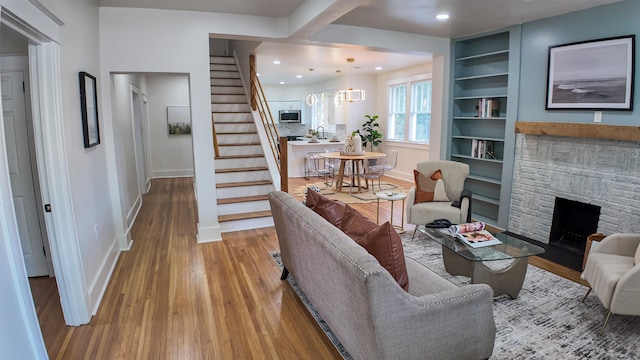 living room featuring built in shelves, a fireplace, and light hardwood / wood-style floors