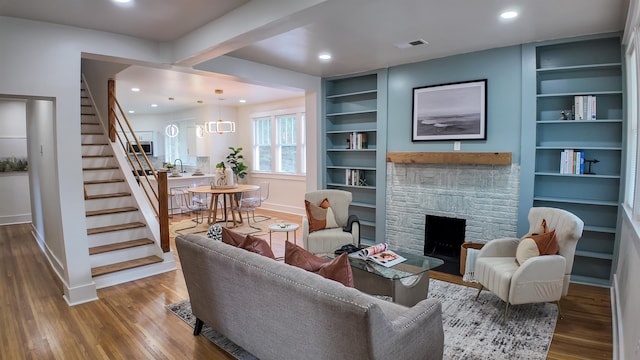 living room featuring built in shelves, a fireplace, hardwood / wood-style flooring, and sink