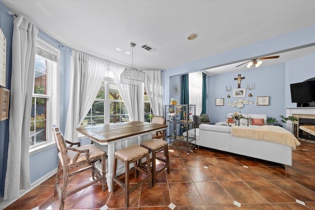 dining room with ceiling fan and a fireplace