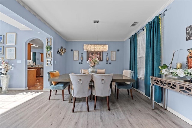 dining room featuring an inviting chandelier, light hardwood / wood-style flooring, and ornamental molding