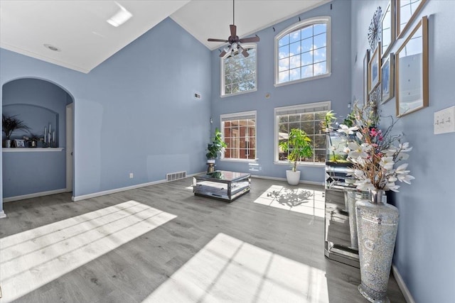 unfurnished living room featuring high vaulted ceiling, plenty of natural light, wood-type flooring, and ceiling fan