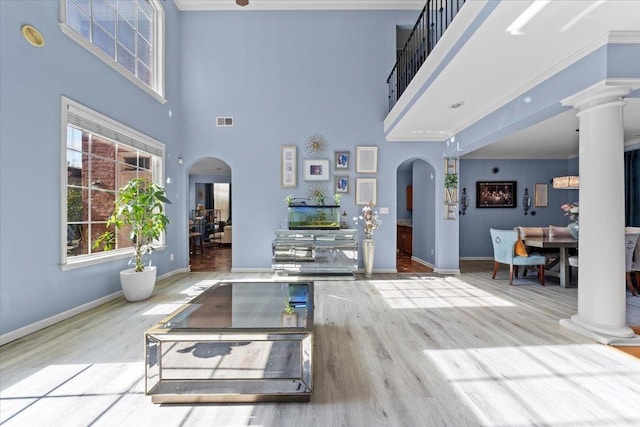 workout room featuring a towering ceiling, light wood-type flooring, and crown molding