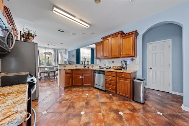 kitchen featuring light stone countertops, appliances with stainless steel finishes, sink, and kitchen peninsula