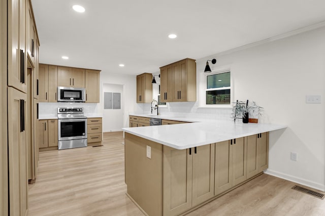 kitchen with kitchen peninsula, light hardwood / wood-style floors, backsplash, and appliances with stainless steel finishes