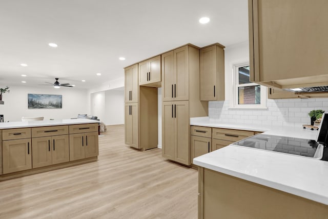 kitchen with tasteful backsplash, light stone counters, stove, ceiling fan, and light hardwood / wood-style flooring