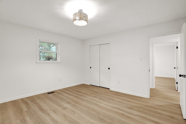 unfurnished bedroom featuring light wood-type flooring and a closet