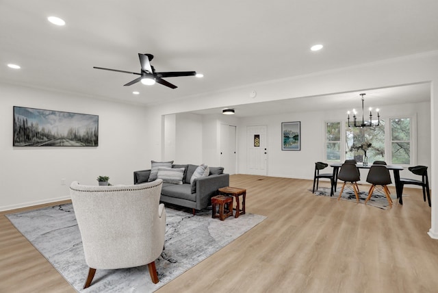 living room with light wood-type flooring and ceiling fan with notable chandelier