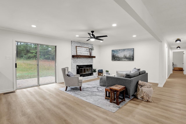 living room featuring a fireplace, ceiling fan, and light hardwood / wood-style flooring