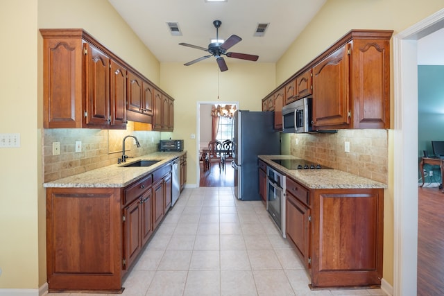 kitchen with decorative backsplash, sink, stainless steel appliances, and light stone counters