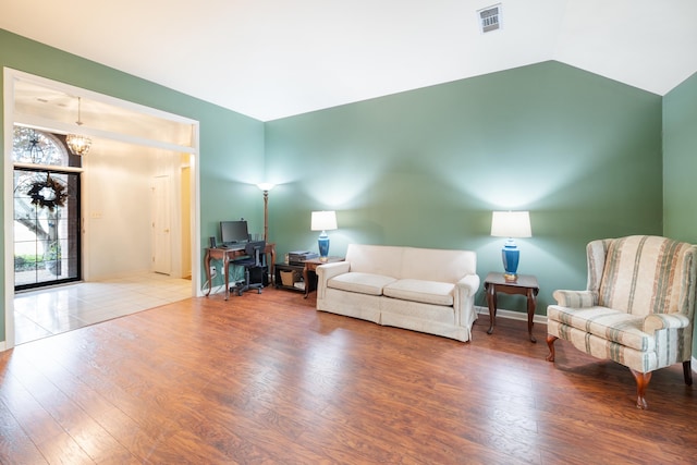 living room with hardwood / wood-style floors, a chandelier, and vaulted ceiling