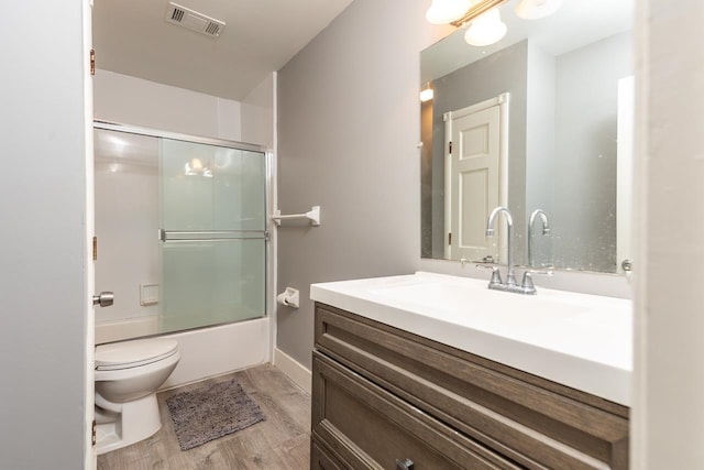 full bathroom featuring shower / bath combination with glass door, toilet, vanity, and hardwood / wood-style flooring