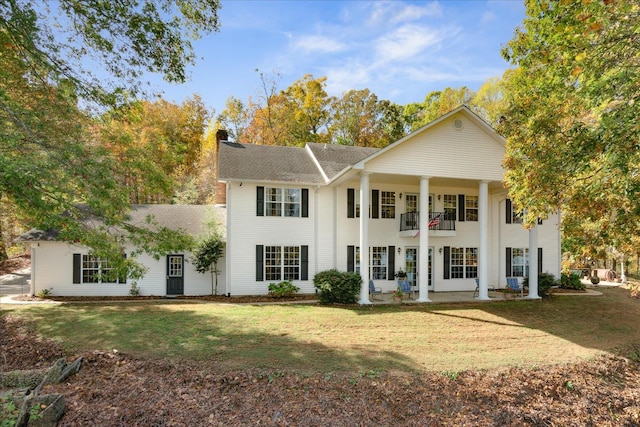 view of front facade featuring a front lawn and a balcony