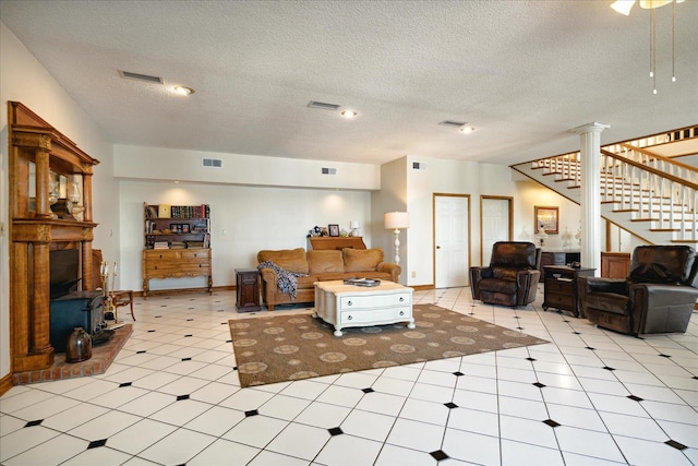 living room with a wood stove, a textured ceiling, and decorative columns