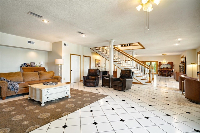 living room with ceiling fan, a textured ceiling, and decorative columns